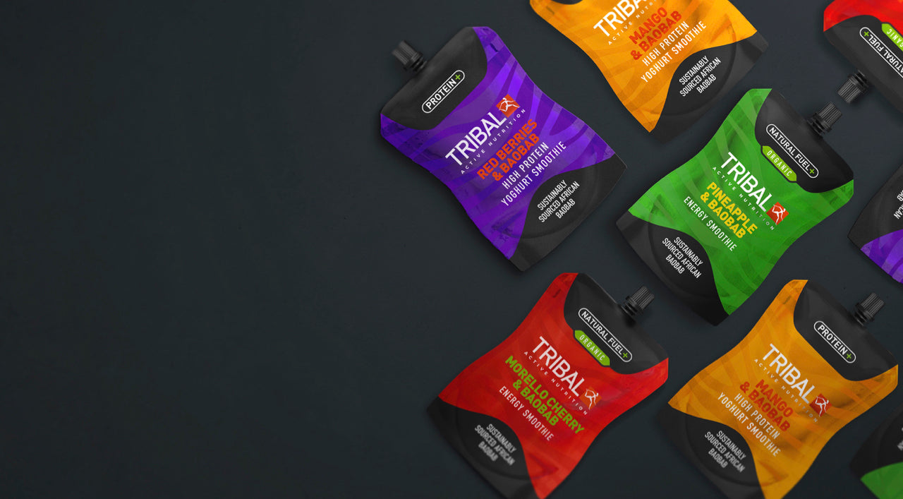 Tribal Active energy smoothie pouches lying on a grey slate background. Each pouch is nutrient-dense, packed full of micronutrients, and a delicious alternative to energy gels. High in vitamin C. Good for gut health. Vegetarian. Vegan. GMO-free.